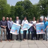 Das Gruppenfoto zeigt die Organisatoren und Sponsoren des Freibadfests mit Plakaten.