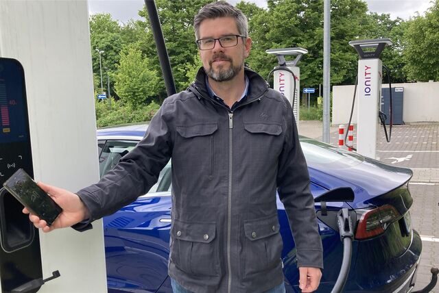Sven Linke steht an der Schnelladestation neben der L’Osteria an der Herzlia-Allee in Marl und bezahlt einen Ladevorgang mit seinem Smartphone.
