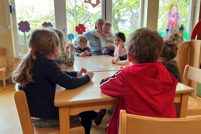 Kinder sitzen in einer Kita am Tisch.