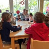 Kinder sitzen in einer Kita am Tisch.