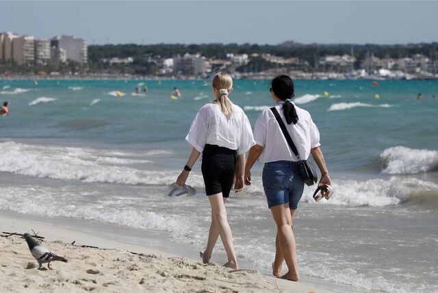 Menschen gehen am Strand von Arenal entlang.