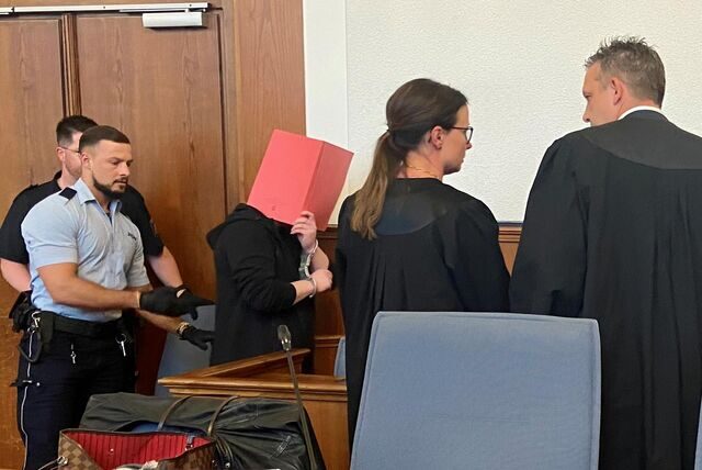 Der Angeklagte verdeckt sein Gesicht im Gerichtssaal mit einem Ordner