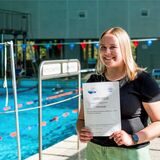 Tabea Baischer steht im Schwimmbad an der Herner Straße in Recklinghausen und hält eine Rettungsschwimm-Urkunde in den Händen.