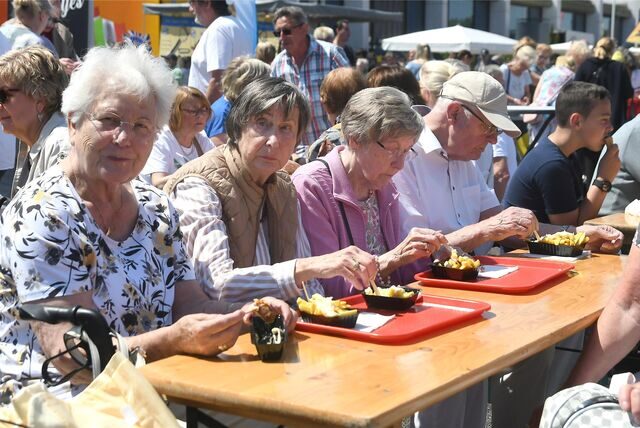 Marktbesucher essen Pommes.