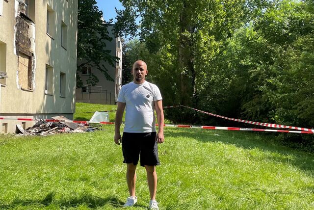 Ibrahim Ghaddar steht auf der Wiese vor dem Haus, in dem er wohnt und in dem es am Sonntag brannte.
