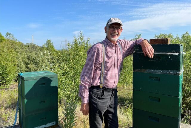 Helmuth Kessen steht zwischen zwei Bienenstöcken auf der Halde Hoheward.