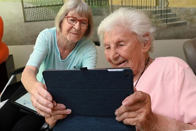 Zwei Rentnerinnen beschäftigen sich in einem Seniorenheim mit ihren Tablets.