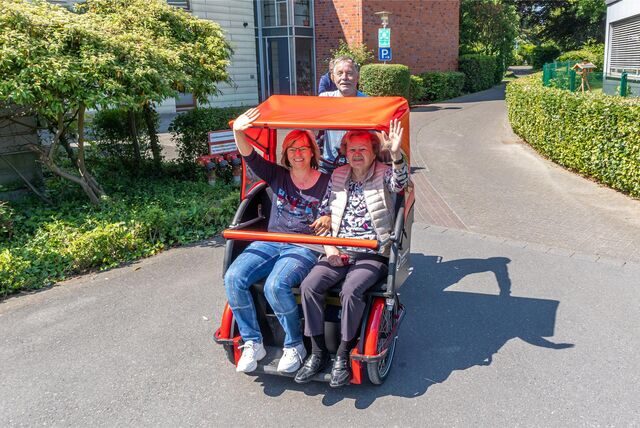 Iris Foggia, Leiterin des Sozialdienstes im Ludgerushaus und Luzie Wagner (86) genießen die Fahrt mit der Fahrrad-Rikscha. Heinrich Mertenskötter (70) tritt in die Pedale.
