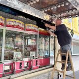 Andre Steffen steht auf einer Leiter und baut die Greifautomaten auf.