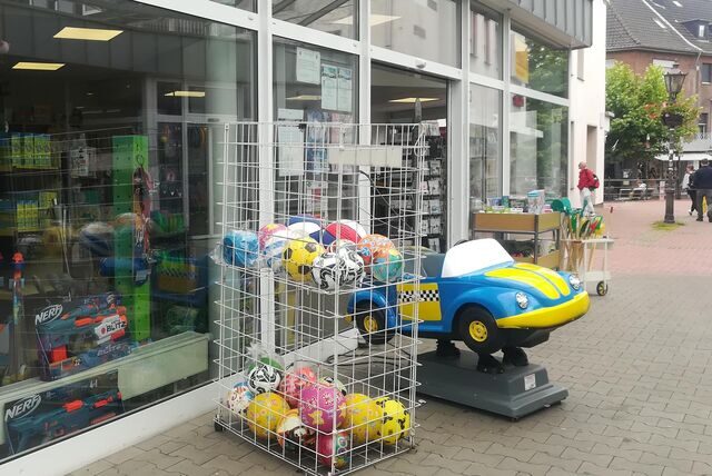 Ein Korb mit Bällen und ein Kinderauto stehen vor einem Spiel- und Schreibwarengeschäft in Haltern.