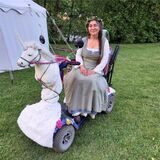 Eine Frau mit einem als Einhorn geschmückten Rollstuhl.
