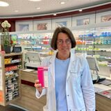 Helga Gödeke steht in ihrer Apotheke und hält ein Medikament hoch.