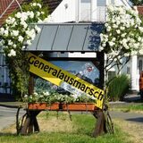 Ein Ortseingangsschild mit einer gelben Banderole, auf der das Wort Generalausmarsch geschrieben steht.