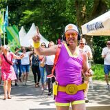 Ein Mann im pink-gelben Sportdress geht vor einer tanzenden Menge durch den Stadtgarten Recklinghausen.