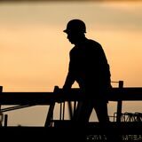 Die Silhouette eines Bauarbeiters im Sonnenuntergang