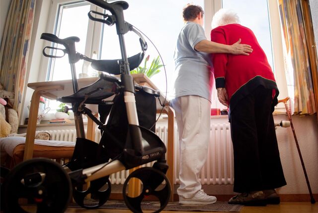 Eine Pflegerin (l) und eine Bewohnerin des Pflegeheims schauen zusammen aus einem Fenster im Wohnbereich des Pflegeheims.