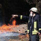 Ein Feuerwehrmann steht vor einem brennenden Waldstück bei Gummersbach.