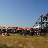 Bunte Sonnenschirme stehen neben Bierzeltgarnituren am Spurwerkturm auf der Halde Waltrop.