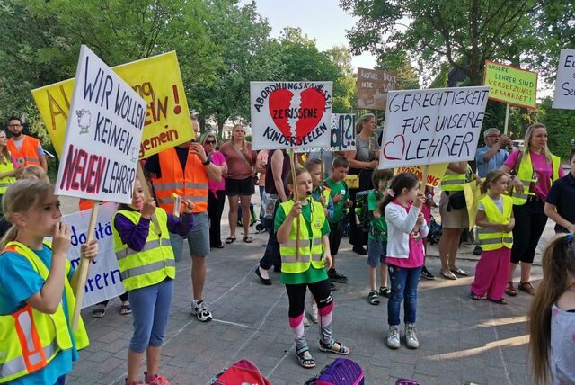 Kinder und Erwachsene halten Protestplakate hoch.
