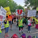 Kinder und Erwachsene halten Protestplakate hoch.