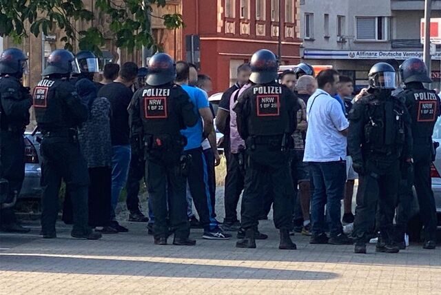 Eine Menschenmasse steht im Bereich Wartburgstraße in Castrop-Rauxel auf Höhe des Netto-Marktes umgeben von Polizei-Einsatzkräften.