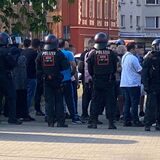 Eine Menschenmasse steht im Bereich Wartburgstraße in Castrop-Rauxel auf Höhe des Netto-Marktes umgeben von Polizei-Einsatzkräften.