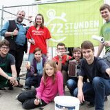 Eine Gruppe posiert mit Malerhandwerkszeug.