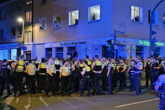 Polizisten stehen am Rande einer Massenschlägerei und riegeln eine Straße ab.