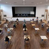 Schülerinnen und Schüler eines Gymnasiums sitzen vor Beginn ihrer schriftlichen Prüfung im Fach Geschichte an ihren Plätzen.