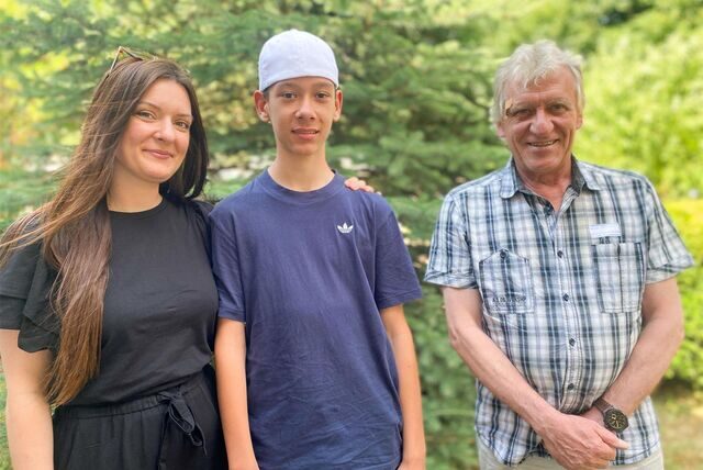 Kathrin Funke legt den Arm um ihren Sohn. Daneben steht Bernd Pahlmann. Im Hintergrund ist eine grüne Tanne zu sehen.
