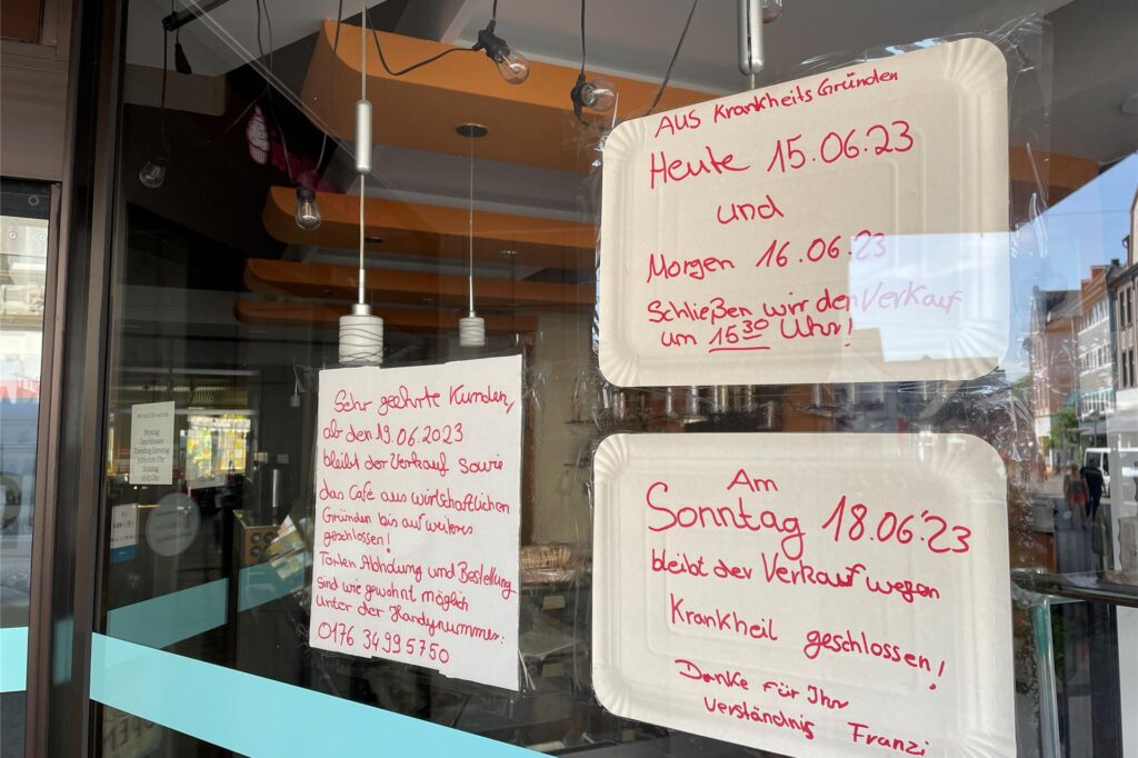 Mit roter Farbe beschriebene Zettel und Pappteller im Schaufenster.