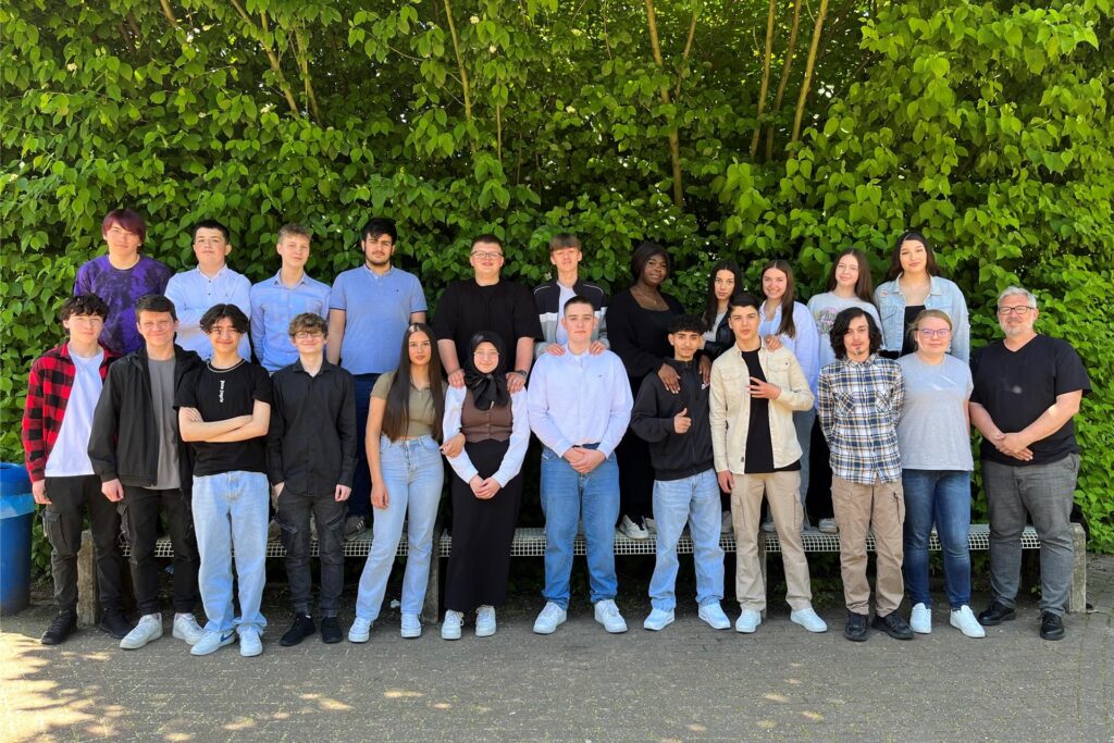 Schülerinnen und Schülern der 10d der Willy-Brandt-Realschule vor einer Hecke.