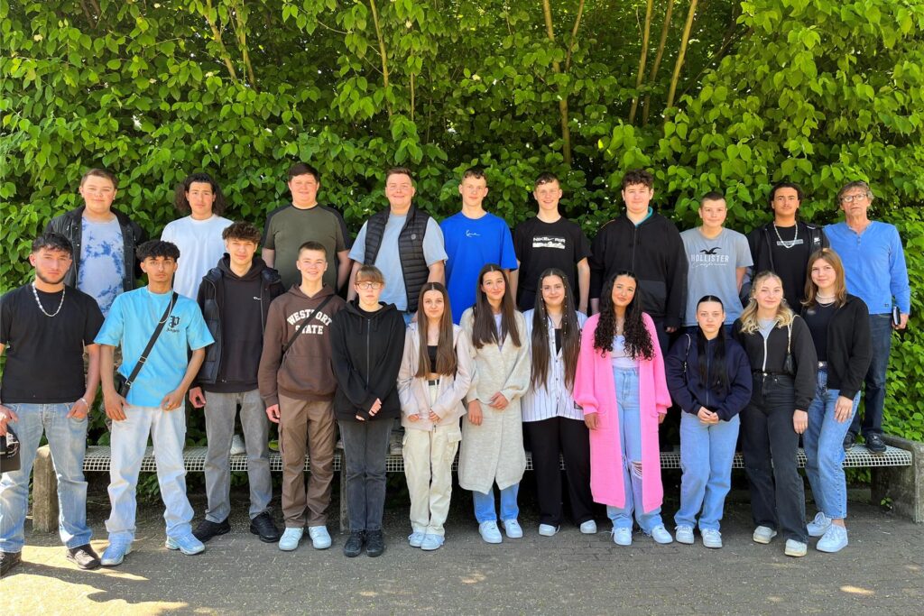 Schülerinnen und Schülern der 10b der Willy-Brandt-Realschule vor einer Hecke.