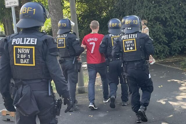 Polizisten führen einen gewalttätigen Fußballfan in einem Trikot von Cristiano Ronaldo ab. Hierbei handelt sich nur um eine Übung für die Fußball-Europameisterschaft 2024.