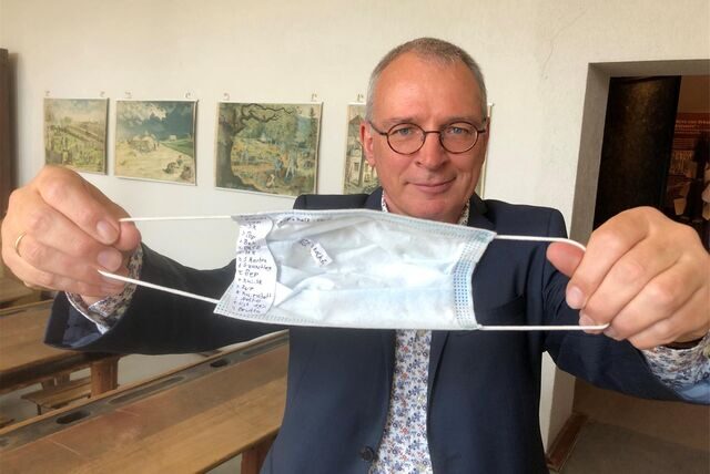 Johannes Gröger zeigt einen Spickzettel in einer Corona-Maske
