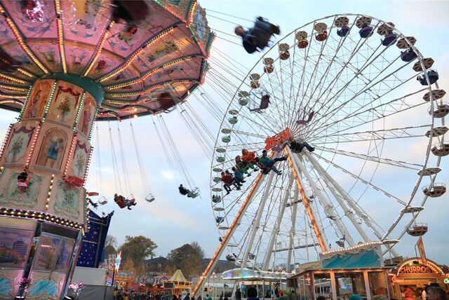 Kirmes-Besucher fahren auf dem Send in Münster mit dem Kettenkarussel, das sich vor dem Riesenrad dreht.