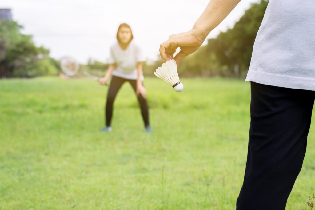 zwei menschen spielen federball auf einer wiese zwei menschen spielen federball auf einer wiese