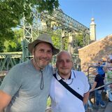 Zwei Männer stehen während der Veranstaltung Extraschicht 2023 vor dem Schiffshebewerk Henrichenburg in Waltrop. Im Hintergrund sind weitere Besucher zu erkennen.