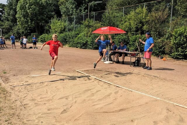 Zwei Jungen springen bei der Sportplatz-Olympiade beim Weitsprung in die Sandgrube.