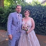 Das Brautpaar Jennifer und Iwan Iwancic hat sich in den Arm genommen und steht für ein Erinnerungsfoto vor eine Hecke.