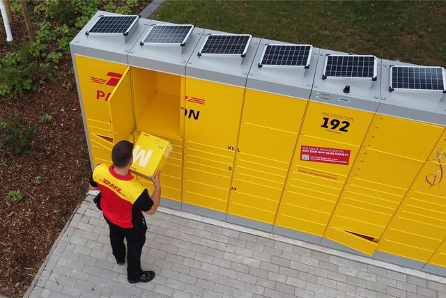 Ein DHL-Bote legt ein Paket in eine Packstation.