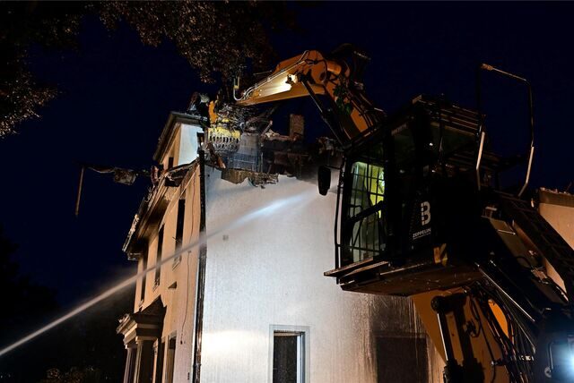 Feuerwehrleute in einem Drehkorb vor einem ausgebrannten Gebäude