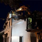 Feuerwehrleute in einem Drehkorb vor einem ausgebrannten Gebäude