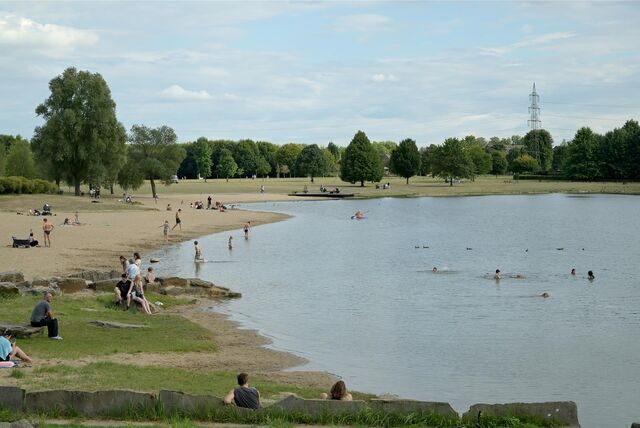 Menschen sonnen sich am Sandstrand oder baden im Horstmarer See.