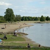Menschen sonnen sich am Sandstrand oder baden im Horstmarer See.