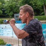 Ralf Moeller souverän mit Pfeife am Beckenrand.