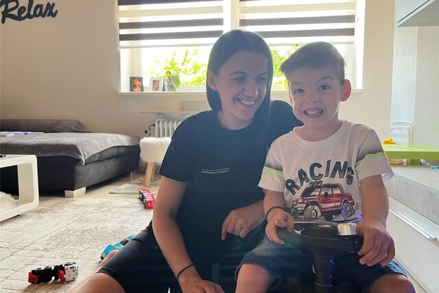 Esliona Cangollari (32) und ihr Sohn Noel Goxhaj (3) sitzen im Wohnzimmer, die Mutter auf einem Teppich, der Dreijährige auf einem Spielauto.