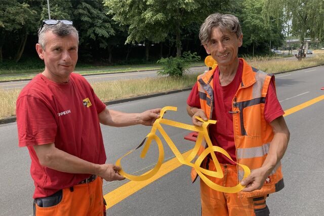 Die Mitarbeiter der Dorstener Firma Zeppelin, Hüseyin Hizarci und Recep Bekmecze, kleben weitere Radfahrsymbole auf den Radschnellweg an der Hervester Straße.