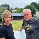Patricia und Oliver Stutz stehen auf ihrem Balkon in Lavesum. Im Hintergrund sind zwei Windräder zu sehen.