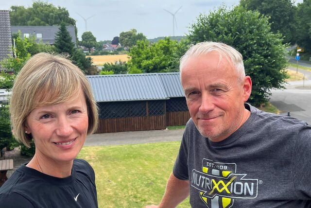 Patricia und Oliver Stutz stehen auf ihrem Balkon in Lavesum. Im Hintergrund sind zwei Windräder zu sehen.